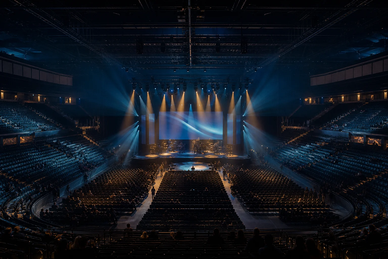 Editorial view across a modern indoor arena toward a stage lit in blue and warm amber